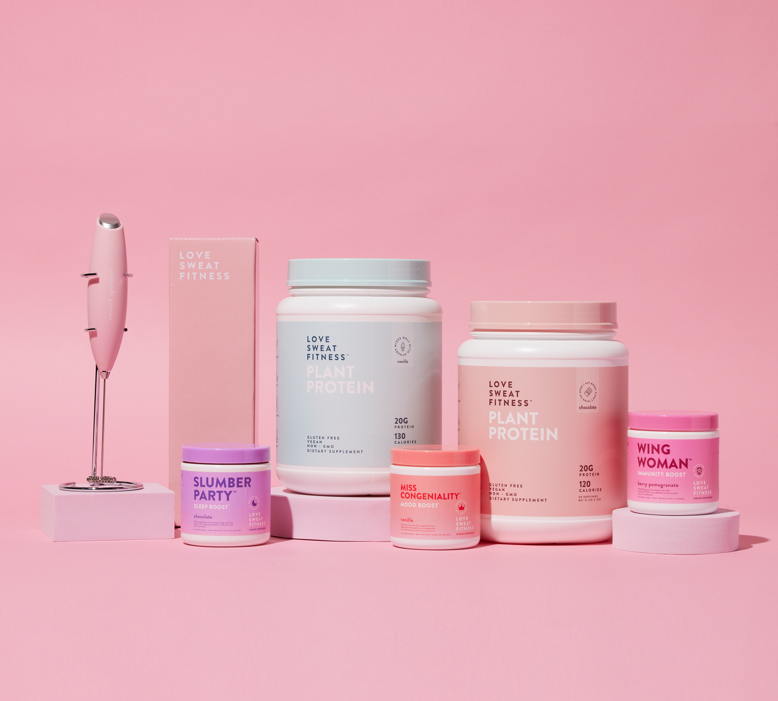 A collection of health and wellness products including protein powders, supplements, and a handheld blender, displayed against a pink background.