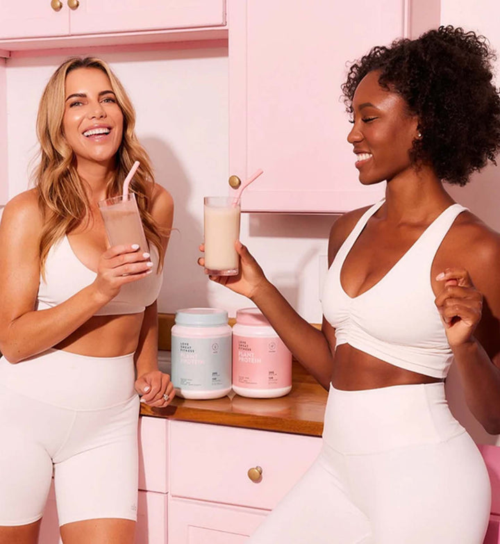 Two girls cheers with protein powder drinks
