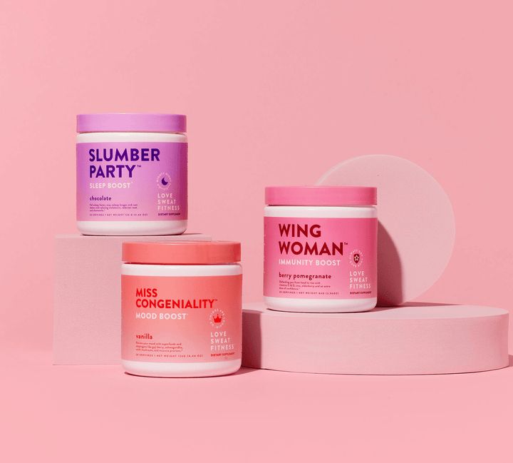 Three containers of wellness supplements in different flavors against a pink backdrop. The containers are labeled 'WING WOMAN', 'SLUMBER PARTY', and 'MISS CONGENIALITY'.