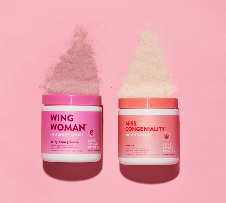 Two containers of supplements, one labeled 'WING WOMAN Immunity Boost' in berry pomegranate flavor, and the other 'MISS CONGENIALITY Mood Boost' in vanilla flavor, both against a pink background.