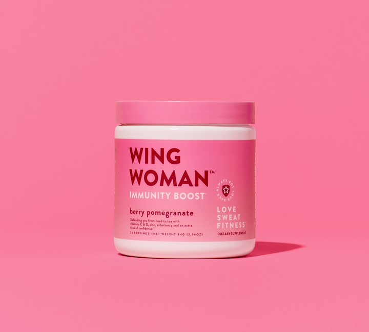 A pink jar labeled 'WING WOMAN Immunity Boost' with a pomegranate-berry flavor, on a pink background.